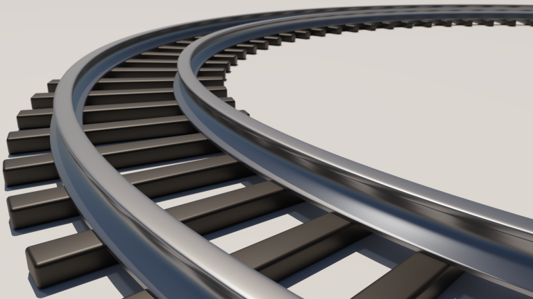 A photograph of a curved section of train track with a low perspective close to the tracks, shallow depth of field.